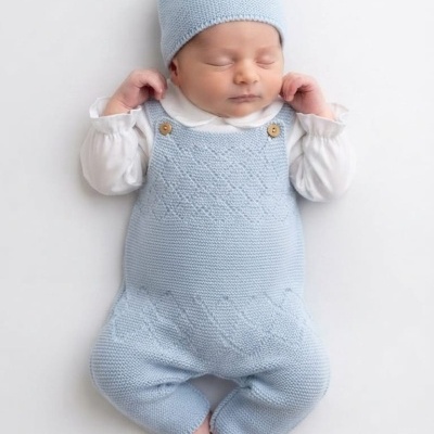 Bebé com roupa de malha azul claro e gorro com pompom