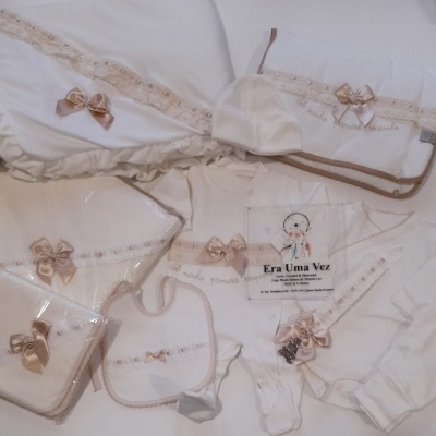 Conjunto de roupas de bebé branco com renda bege e laços cor de rosa