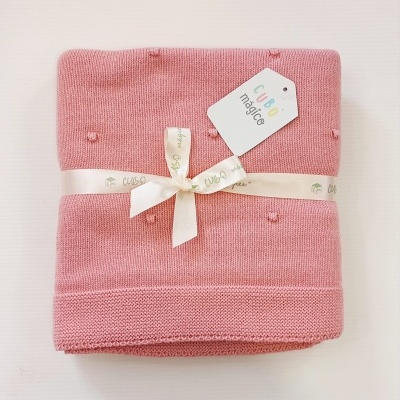 Manta de malha rosa com fita branca e etiqueta CUBO mágico