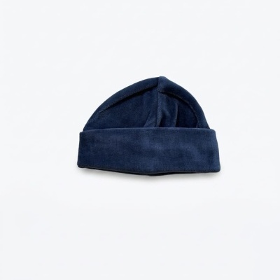 Gorro azul escuro de tecido com dobra larga numa superfície branca