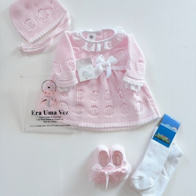 Conjunto de roupa de bebé rosa claro com vestido, touca, sapatinhos e collants.