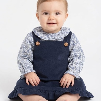 Bebé sentado veste vestido azul escuro com camisa floral branca e azul.