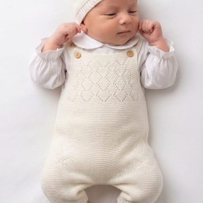 Bebé com roupa de malha branca e touca
