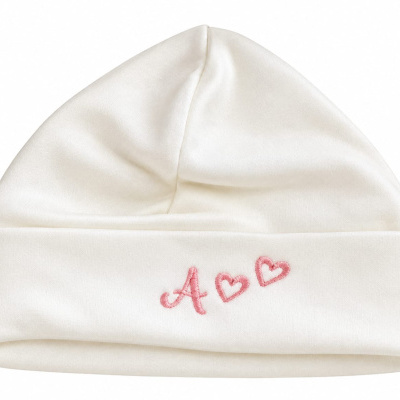 Gorro branco com bordado cor-de-rosa da letra A e dois corações.