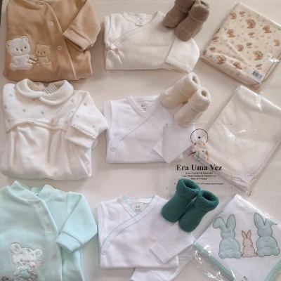 Conjunto de roupa de bebé com bodies, macacões, botinhas e fraldas em diversas cores e padrões, incluindo ursinhos e coelhos