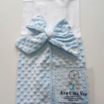 Manta para bebé azul claro texturada com padrão de bolinhas e laço decorativo