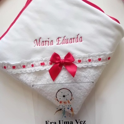 Toalha de bebé branca com borda rosa, laço, renda e nome bordado 'Maria Eduarda'.