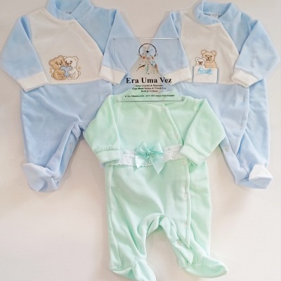 Três pijamas de bebé azuis e verde claro com ursinhos bordados e laço, sobre fundo branco.