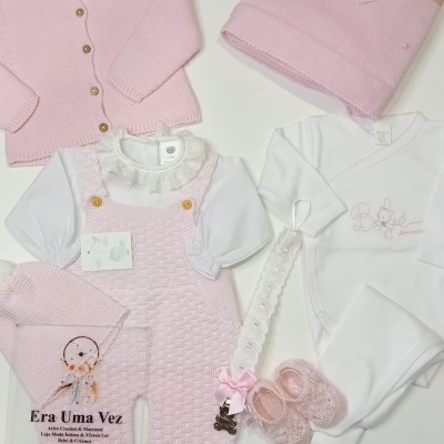 Conjunto de roupa de bebé rosa e branco com acessórios e manta dobrada