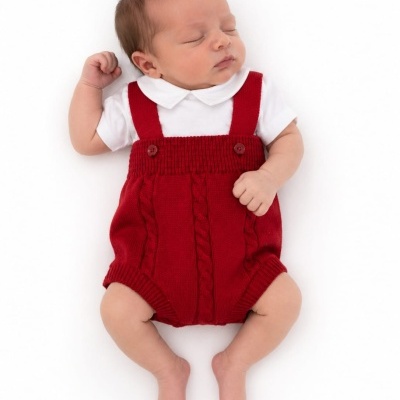 Bebé a dormir com macacão vermelho de malha e camisola branca