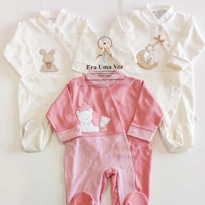 Três macacões de bebé brancos e rosa com bordados e padrões riscado, apresentados em fundo branco.