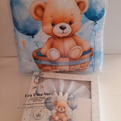 Conjunto de roupa de bebé com urso e balões azuis em almofadas e embalagem branca com estrelas