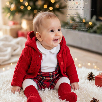 Bebé com roupa vermelha e branca sentado em carpete branca com decoração de Natal