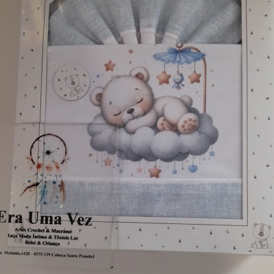 Lençóis para bebé azuis com padrão de urso a dormir em nuvem e estrelas em embalagem branca.