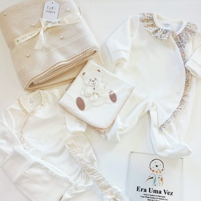 Conjunto roupa bebé branco com manta bege e faixa laço sobre fundo branco