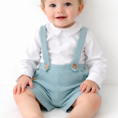 Bebé loiro em roupa branca e azul sentado