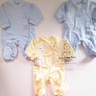 Três pijamas de bebé em azul e amarelo com botões de pressão, bordados e laços