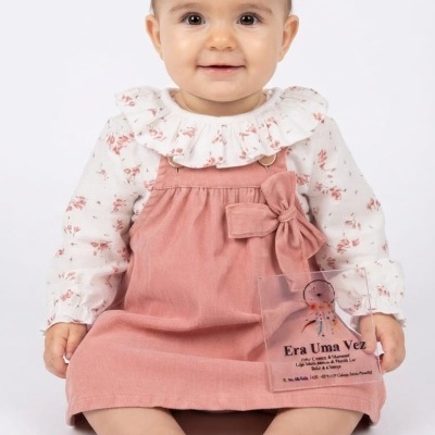 Bebé com vestido rosa e blusa floral branca sentada