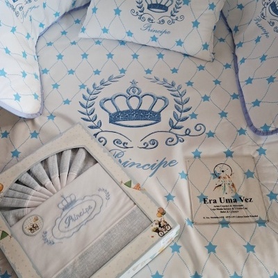 Roupa de cama branca com estrelas azuis e bordado de coroa azul e palavra Príncipe.