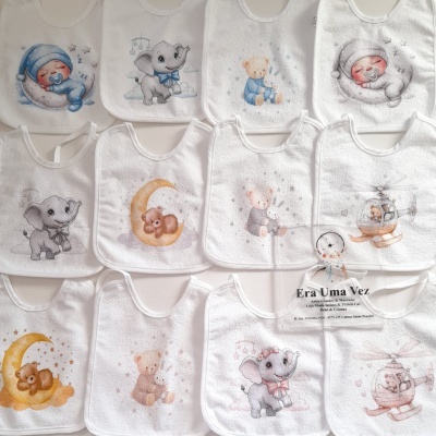 Babetes brancos para bebé com desenhos infantis coloridos dispostos em fila