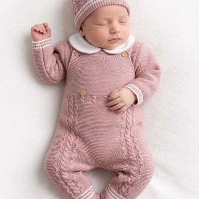 Bebé a dormir com fato e gorro de malha rosa com padrão trançado