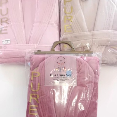 Três robes femininos embalados em plástico transparente, cores coral, rosa claro e bege.