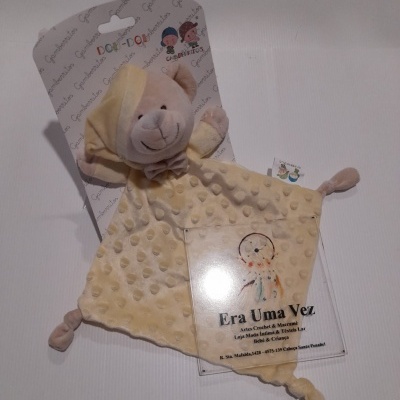 Pelúcia de bebê cor creme com cabeça de ursinho sorridente e etiqueta informativa