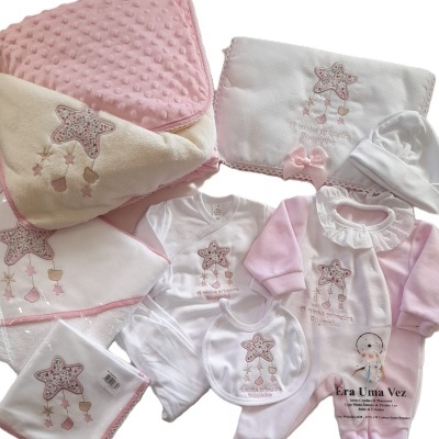 Conjunto de roupa e acessórios para bebé em tecido branco e rosa com padrão de estrela floral e texto bordado.