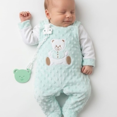 Bebé com macacão azul claro de veludo texturizado e estampa de urso
