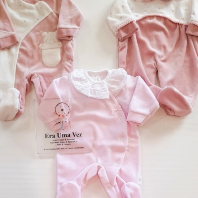 Três macacões de bebé em rosa e branco com texturas e estampados delicados.