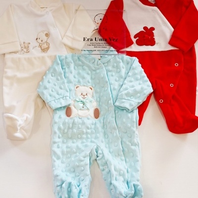 Três macacões de bebé em azul claro, branco e vermelho com bordados de ursinho e coelhos.