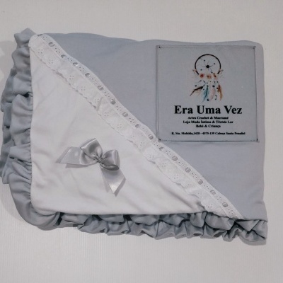 Manta de bebé branca e cinzenta com laço e renda, etiqueta com texto e imagem de apanhador de sonhos