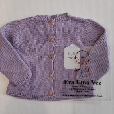 Casaco de bebé lilás com botões de madeira e etiqueta em fundo branco.