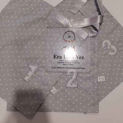 Sacolas de tecido cinza com estrelas brancas e números bordados, fita cinza satinada, placa transparente com texto Era Uma Vez
