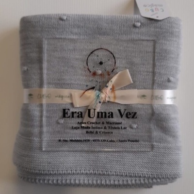 Manta cinza clara em malha com laço branco e etiqueta com texto
