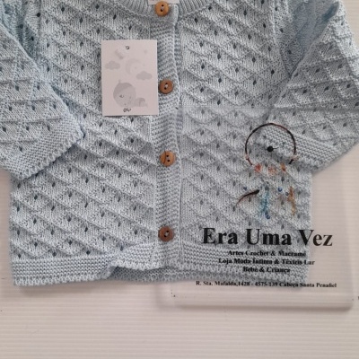 Casaco azul claro de malha para bebé com botões castanhos e padrão tricotado.