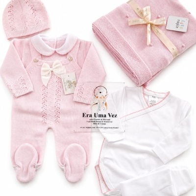 Conjunto de roupa de bebé rosa e branca com manta e gorro sobre fundo branco