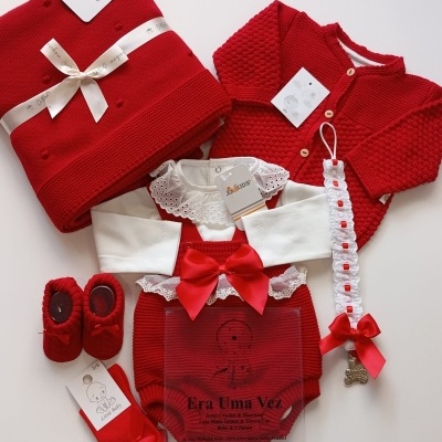 Conjunto de roupa de bebé vermelho e branco com vários acessórios sobre fundo branco