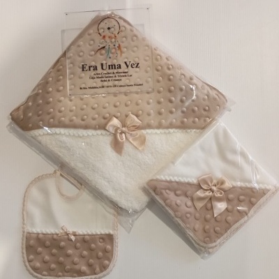 Conjunto de capa de banho, toalha e babete para bebé em branco e bege com laços.