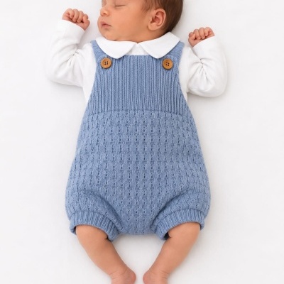 Bebé com jardineira azul clara e body branco de manga comprida deitado