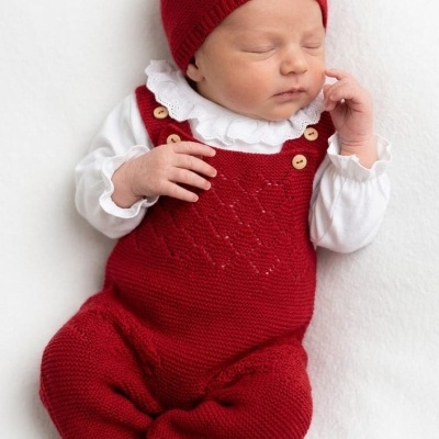 Bebé a dormir com roupa vermelha e branca sobre fundo branco