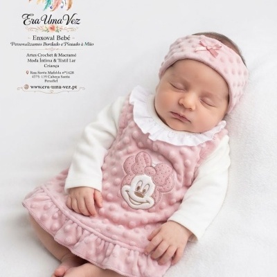 Bebé dormindo com vestido rosa bordado da Minnie e faixa de cabeça rosa