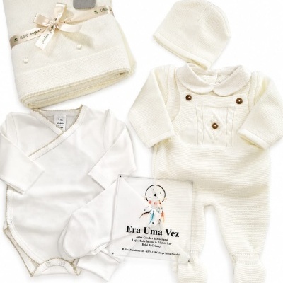 Conjunto de roupa de bebé em tons creme com body, conjunto em malha, gorro, manta e saco com texto