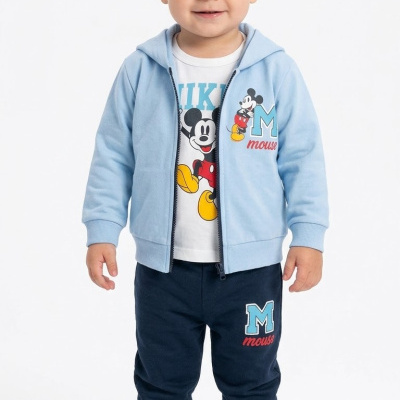 Criança vestindo roupa com tema do Mickey Mouse, casaco azul, t-shirt branca e calças azul-escuras.
