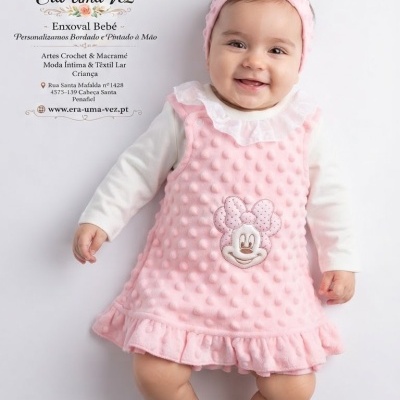 Bebé com vestido rosa e fita cor de rosa com texto de publicidade da marca Era Uma Vez Enxoval Bebé