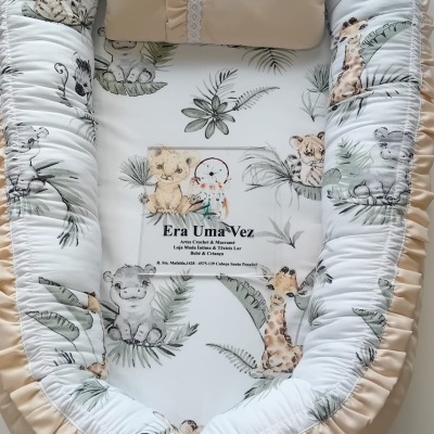 Ninho de bebé com padrão de animais selvagens e almofada bege com renda branca