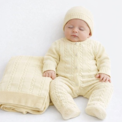 Bebé com fato de malha amarelo claro e manta