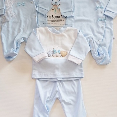 Conjuntos de roupa de bebé azul claro com ursinhos, botões e detalhes em tecido branco e bege sobre fundo branco.