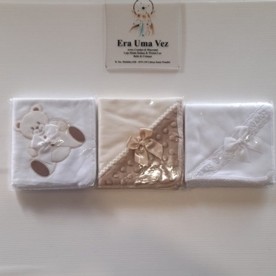 Paninhos de bebé embalados em plástico com decoração branca e bege