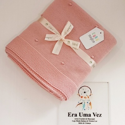 Manta rosa de malha com fita e etiqueta perto de placa com texto